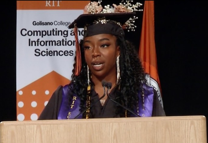 Yanika Telus at the podium, delivering the student address at the Golisano College of Computing and Information Sciences commencement at RIT